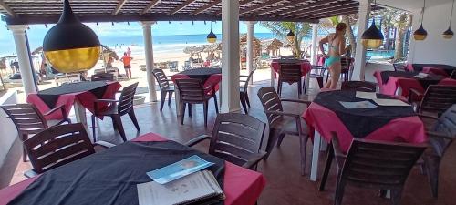 a restaurant with tables and chairs and the beach at Hotel Universal Beach in Hikkaduwa