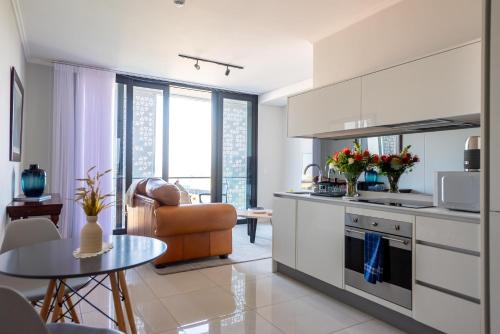 a kitchen with white cabinets and a table in a room at Witshire Luxury apartment, Ellipse in Midrand