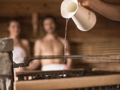 a person holding a cup of coffee in a bath tub at Waldhof Fuschlsee Resort in Fuschl am See