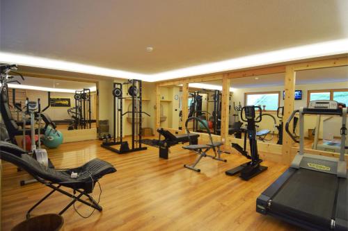 a gym with several treadmills and machines in a room at Hotel Ciasa Ai Pini in San Cassiano