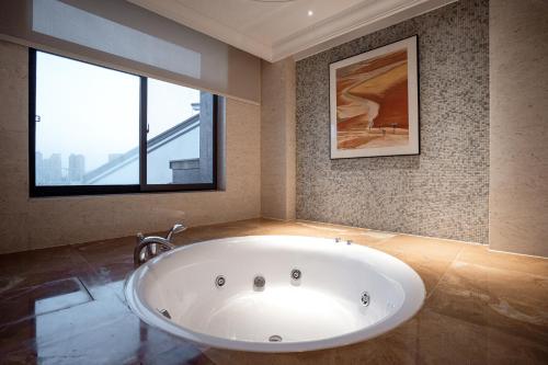 a large bath tub in a bathroom with a window at Yancheng Shuicheng Hotel in Yancheng