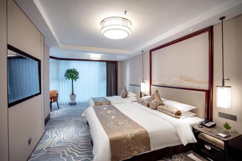 a hotel room with two beds and a flat screen tv at Yancheng Shuicheng Hotel in Yancheng