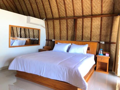 een slaapkamer met een groot bed met witte lakens bij Sedana Yoga Resort in Jembrana