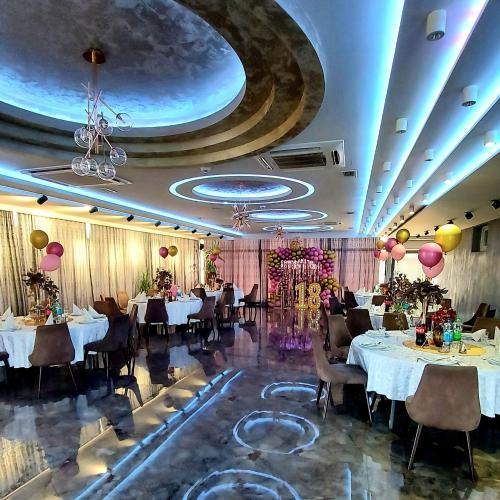 a banquet hall with tables and chairs and a ceiling at Hotel River in Bijeljina