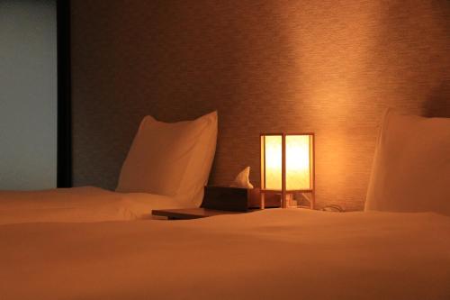 a hotel room with two beds and a lamp at Kyonoyado Nijo Yumeya in Kyoto
