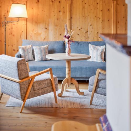 a living room with a blue couch and a table at Waldhof Fuschlsee Resort in Fuschl am See