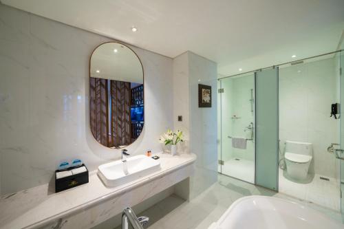 a bathroom with a sink and a mirror and a tub at Northern Charm Hotel in Ho Chi Minh City