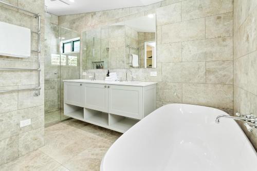 ヌーサヘッズにあるPeaceful & Stylish Retreat, Noosa Headsの白い洗面台とシャワー付きのバスルーム