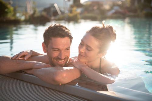 a man and a woman in a swimming pool at Waldhof Fuschlsee Resort in Fuschl am See