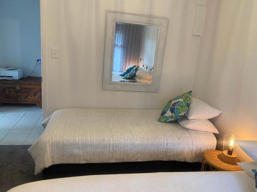 a small bedroom with a bed and a mirror at Sunrise on Main in Tairua