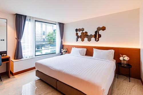 a bedroom with a large bed and a window at Frame Hotel Bangkok in Bangkok