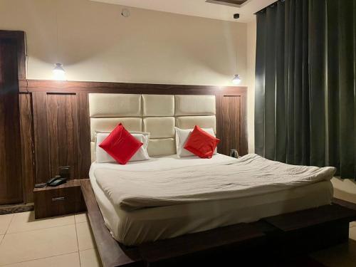1 dormitorio con 1 cama con 2 almohadas rojas en Hotel Himgiri Pakki Daki en Jammu