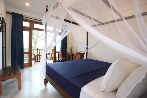 PearlDrop Waves Mirissa في ميريسا: غرفة نوم بسرير مع مظلة