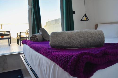 a bed with a purple blanket on top of it at Chic Penthouse industrial-style in Mosta