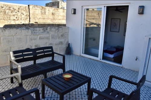 d'une terrasse avec 2 chaises, une table et une fenêtre. dans l'établissement Chic Penthouse industrial-style, à Mosta