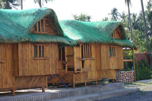 a large wooden house with a green roof at Hana-Natsu Resorts Pool & Hotel in Maybayo