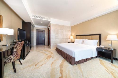 a hotel room with a bed and a desk and a television at Oriental Ginza Hotel Shenzhen in Shenzhen