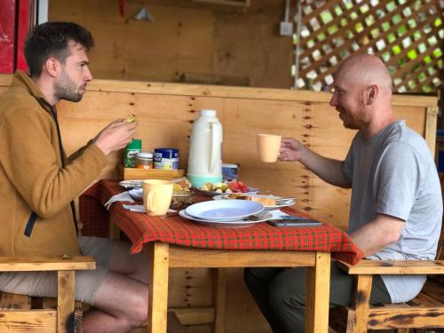 モシにあるKilibase Hotelの二人の男がテーブルに座って食べ物を食べる