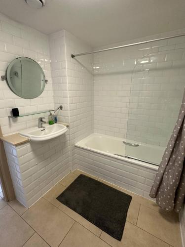 bagno con lavandino, vasca e specchio di Bright And Airy Islington Apartment a Londra