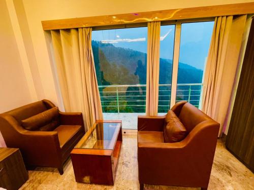 Hotel candlewood Shimla في شيملا: غرفة معيشة مع كرسيين ونافذة كبيرة