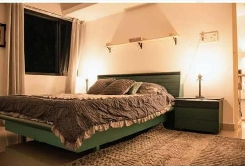 a bedroom with a green bed and a window at White House in Canacona