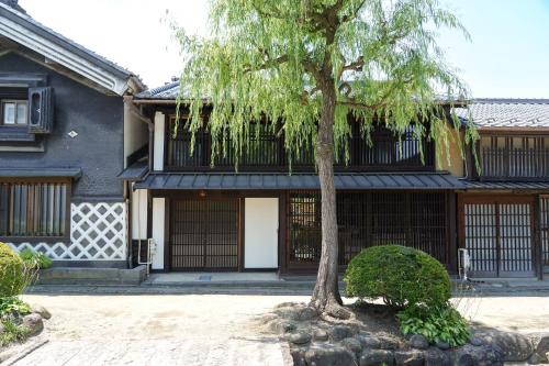 une maison avec un arbre en face dans l'établissement 海野宿一棟貸し宿 上州屋 Unnojuku Joshuya, à Tomi