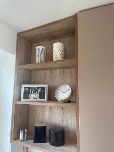 a shelf with a clock and vases on it at Apartament Szczytno II in Szczytno