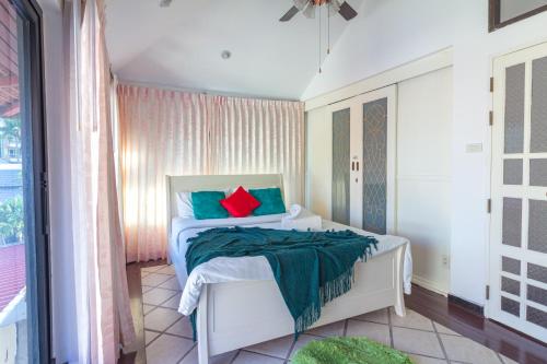 sypialnia z łóżkiem z zielonymi i czerwonymi poduszkami w obiekcie Thabali Oasis:3BHK private pool villa + Sauna w Pattaya South
