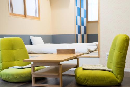 a room with a table and two green chairs at Guesthouse ZenNichi in Kyoto