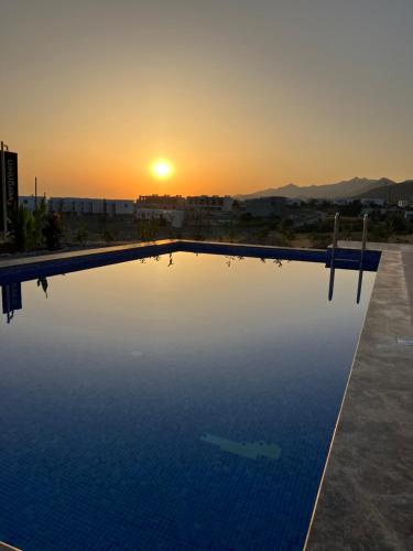 a swimming pool with the sunset in the background at Bungalow med privat saltvannsbasseng på Dejablue in Kalogrea