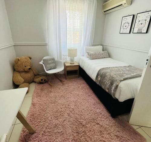 a bedroom with a bed and a teddy bear on a rug at musgrave manors villa in Durban