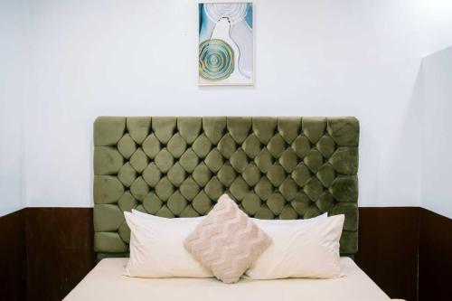 a bed with a green padded headboard and two pillows at Arka's Elegant Condos in Zamboanga