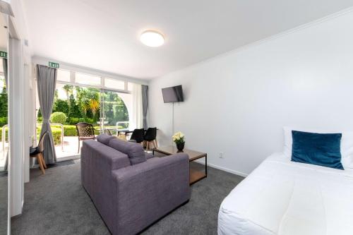 a bedroom with a bed and a couch and a room with a window at Aarangi Motel in Auckland