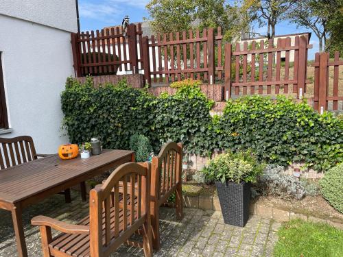 a patio with a wooden table and chairs and a fence at Ferienwohnung in der Vulkaneifel "Opp der Holl" in Brockscheid