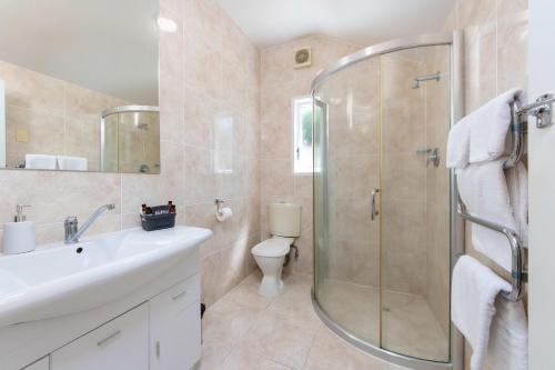 uma casa de banho com um chuveiro, um lavatório e um WC. em Aarangi Motel em Auckland