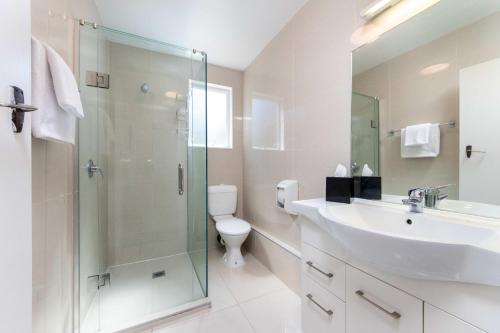 a bathroom with a sink and a shower and a toilet at Aarangi Motel in Auckland