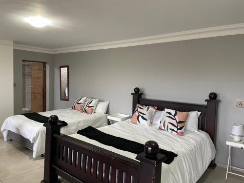 two beds in a bedroom with white and pink pillows at Oaktree in Ermelo