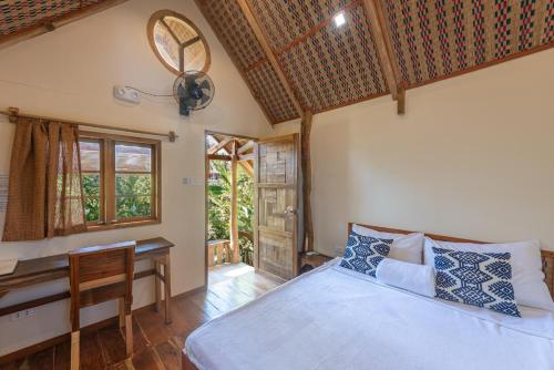 a bedroom with a bed and a desk at Camanolo Homestay in General Luna