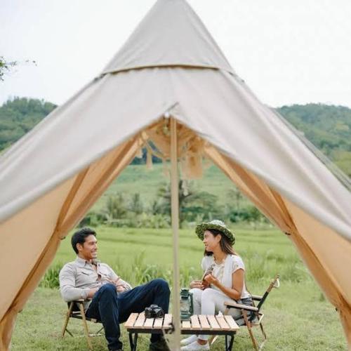 un homme et une femme assis dans une tente dans l'établissement CAMPING GROUND, à Bukittinggi