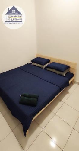 a bed with blue sheets and two green pillows on it at HOMESTAY haROOManizz in Kangar