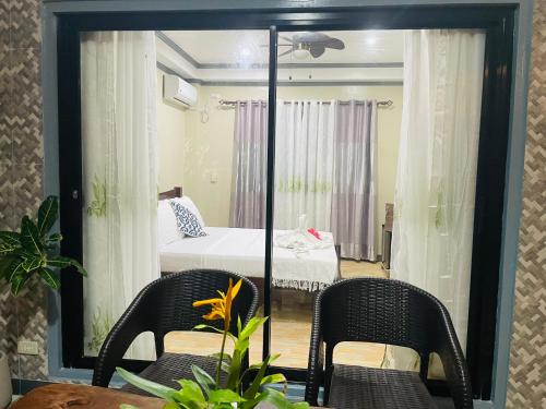 a room with a bed and two chairs and a mirror at White Beach Front and Cottages in Buruanga