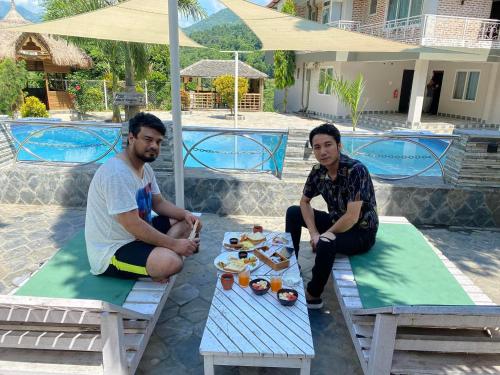 two men sitting at a picnic table with food on it at Hills and Horizon Resort in Benighāt
