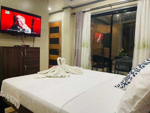 a bedroom with a bed with a tv on the wall at White Beach Front and Cottages in Buruanga