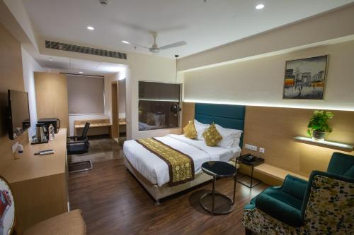 a hotel room with a bed and a chair at Hotel Midori Vithalapur in Vithalpur