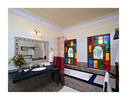 Pātan的住宿－帕坦瑪哈度假村，一间带水槽和彩色玻璃窗的浴室