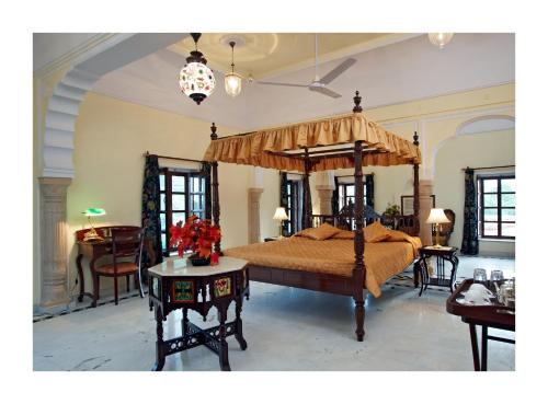 a bedroom with a canopy bed with a table at Patan Mahal in Pātan