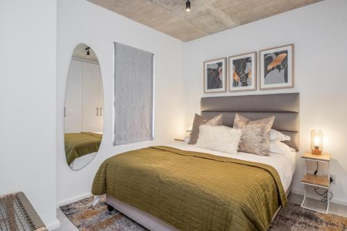 een slaapkamer met een groot bed en een spiegel bij Luxury Escape at Alphen Glen Constantia in Kaapstad