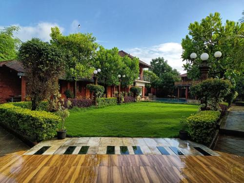 a large yard with a green lawn with trees at Red Stone Resort in Alibag