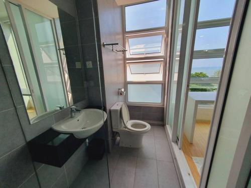 a bathroom with a toilet and a sink and window at F1E DeOwl Beachfront Balcony Seaview karaoke condo in Tanjung Bungah