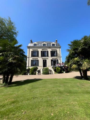 a large white house with palm trees in front of it at Domaine de la Belvaudière - luxueux - 24H du Mans - 20p - Rêve au Mans in Saint Pavace